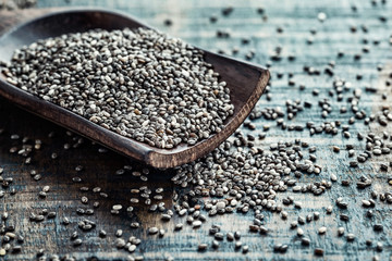 Chia seeds in a wooden scoop on a wooden rustic background