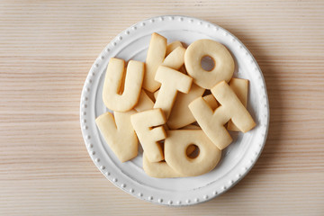 Plate with cookie alphabet on wooden  table