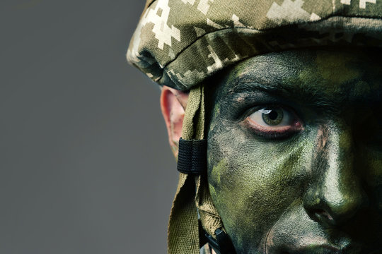 Close Up View Of Soldier With Face Paint On Grey Background