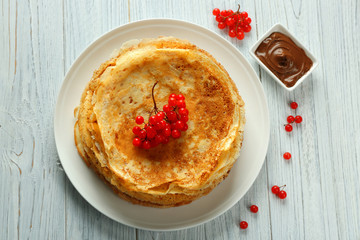 Delicious pancakes decorated with viburnum on plate