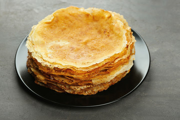 Plate with tasty pancakes on grey table
