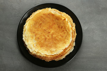 Plate with tasty pancakes on grey table