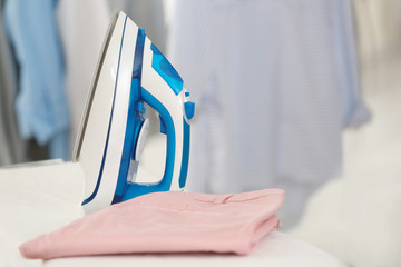 Electric iron and pants on ironing board in room