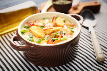 Delicious beer cheese soup with croutons and fried bacon on table