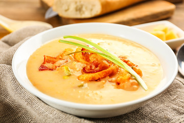 Delicious beer cheese soup with onion and fried bacon on table