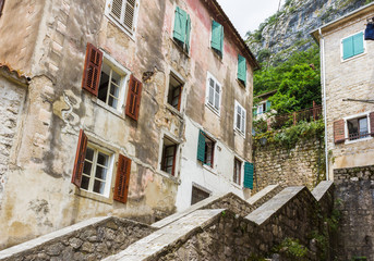 Old Mediterranean house and facade in the town of Kotor, Montenegro. Walls of building, windows with open and closed shutters
