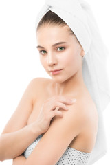 Beautiful young brunette woman with clean face and towel on her head applying moisturizer cream on shoulders. Beauty spa model girl perfect fresh clean skin. Youth and skin care concept. Isolated.