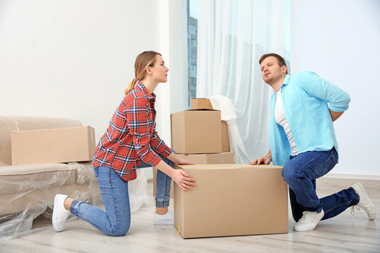 Man suffering from ache while moving box in room