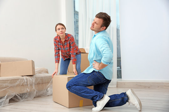 Man suffering from ache while moving box in room