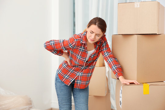 Young Woman Suffering From Pain After Moving Heavy Box