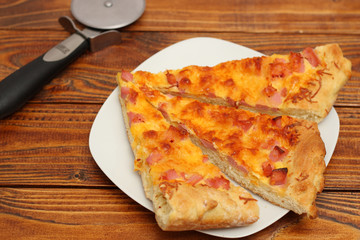 Pizza on plate with cutter on wood table