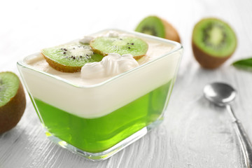 Tasty jelly dessert with kiwi and cream on wooden table