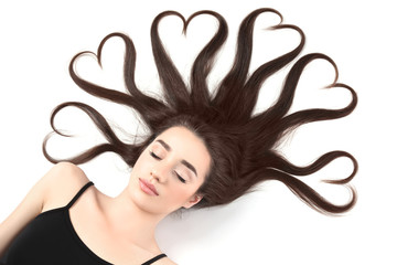 Beautiful young woman with hair in shape of hearts on white background