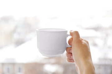 Blank white cup in hand, closeup © Africa Studio