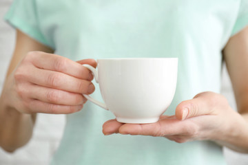 Fototapeta na wymiar Blank white cup in hands, closeup