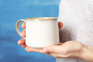 Fototapeta na wymiar Blank white cup in hands, closeup