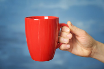 Obraz premium Blank red cup in hand, closeup