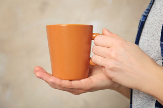 Blank color cup in hands, closeup