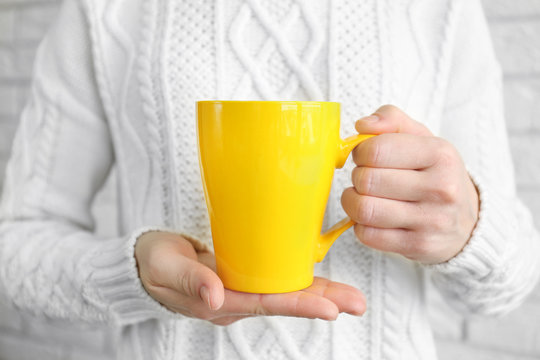 Blank yellow cup in hands, closeup