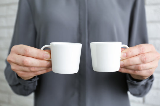 Blank white cups in hands, closeup