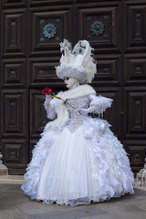Fototapeta na wymiar Donna mascherata a Venezia con rosa rossa nelle mani 