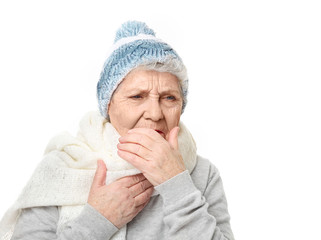 Portrait of coughing elderly woman in warm outfit on white background