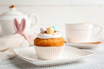 Plate with delicious Easter cupcake on table