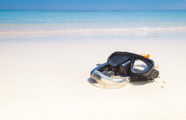 Mask and snorkel in the surf on the sandy beach.