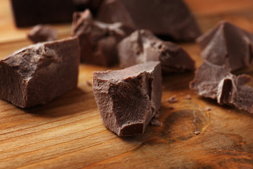 Broken chocolate pieces on wooden background
