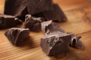 Broken chocolate pieces on wooden background