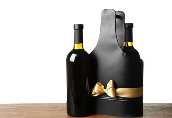 Table with wine bottles and gift box on white background