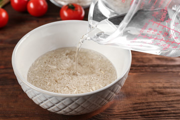Cooking concept. Pouring water in bowl with rice