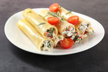 Delicious stuffed cannelloni with cherry tomatoes on plate