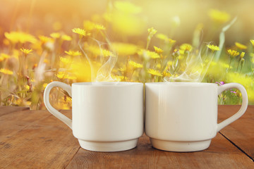 Two cups of coffee a wooden table in front of spring landscape