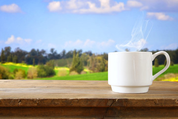 Cup of coffee a wooden table in front of spring landscape