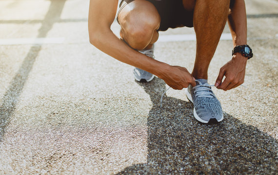 Running shoes, Close up of runner man trying shoelaces getting ready for run on the outdoor street. Sport and exercise concept