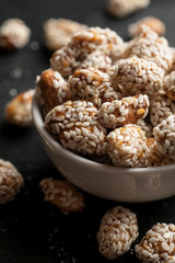 Roasted peanuts covered with sesame in white ceramic bowl, vertical
