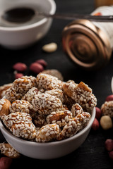 Roasted peanuts covered with sesame in white ceramic bowl and other stuff in the background, vertical
