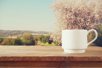 Cup of coffee a wooden table in front of spring landscape