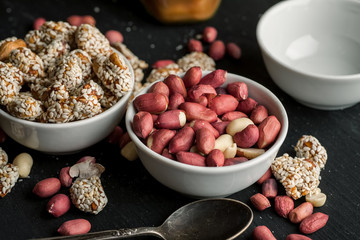 Different peanuts in ceramic bowls on a wooden table