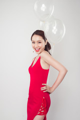 Pretty young asian woman wearing red dress with balloons in hand.