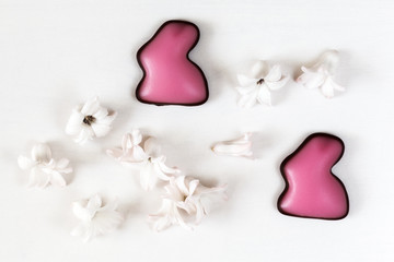 Zwei Fondant-Osterhasen mit Frühlingsblüten (Hyazinthen) auf einem Holzuntergrund