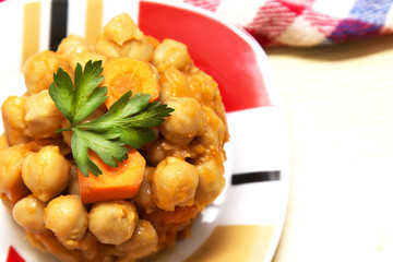 Chickpeas with tomato and carrot on wooden table plate