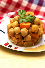Chickpeas with tomato and carrot on wooden table plate