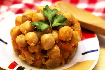 Chickpeas with tomato and carrot on wooden table plate