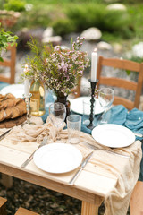 spring festive lunch an outdoors, wedding decor of a table, table layout, the fresh cut bread, bouquet of wild flowers in a vase.