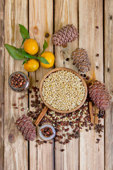 Cedar nuts and cones on wooden table. Tangerines, rolls of cinnamon, star anise