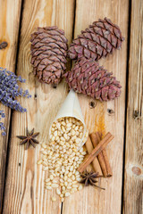 Cedar nuts, rolls of cinnamon, pine cones, bouquet of lavender and star anise on wooden table