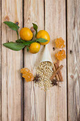 Cedar nuts and cones on wooden table. Tangerines, rolls of cinnamon, star anise