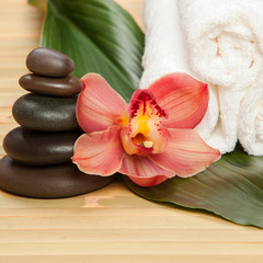 Fototapeta na wymiar Spa background. White towels on exotic plant, beautiful orchid flower and balancing stones for relax spa massage and body treatment. Asian medicine with aroma and stone therapy for beauty healthy body